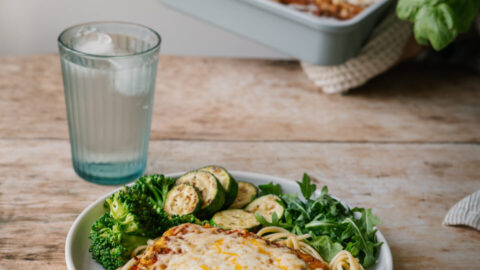 ofu parmigiana gratiné avec sauce tomate, fromage fondu et basilic frais, servi dans une assiette