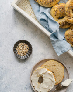 Assaisonnement Everything Bagel maison dans un pot en verre avec un bagel maison garni de graines et d'épices