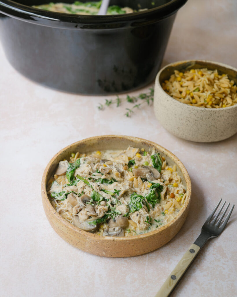 Poulet crémeux aux champignons à la mijoteuse servi comme repas complet équilibré dans une assiette sur de l'orzo recette de nutritionniste