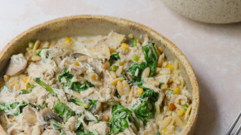 Poulet crémeux aux champignons à la mijoteuse servi sur de l'orzo avec une sauce onctueuse au parmesan et des épinards.