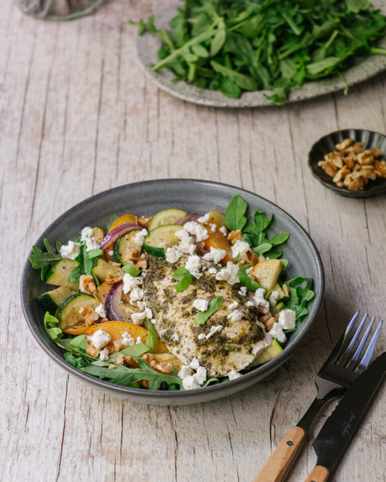 poulet au pesto sur la plaque avec courgettes et pêches grillées, servies dans un bol avec feta. recette de semaine facile sur la plaque