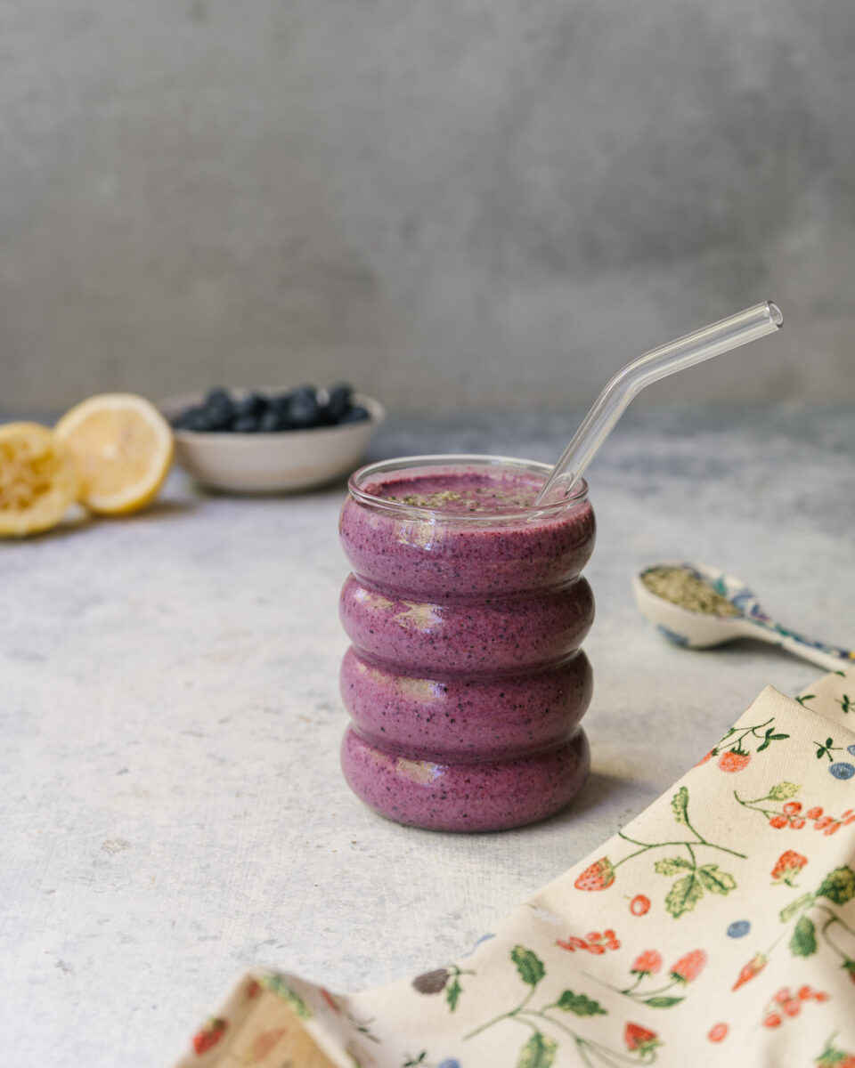 Smoothie bleuets et citron garni de bleuets frais, de zeste de citron et de graines de chanvre dans un verre